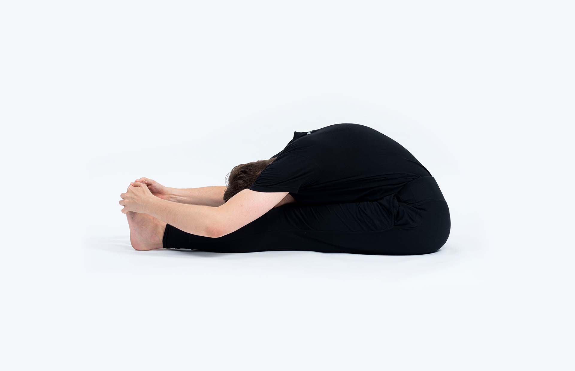 A person reaching into Paschimottanasana (Seated Forward Bend)